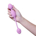 Hand holding a lilac Wellness Raine vibrating kegel ball with a smooth silicone finish and flexible tail.