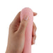 Hand holding a compact, smooth pink iroha mai TOKI personal care device with ergonomic design.