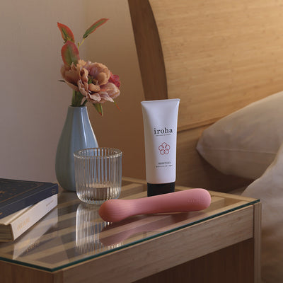iroha mai TOKI in soft pink with iroha moist gel on a bedside glass table next to a flower vase and books