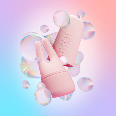 Pink VUSH Swish Dual Tip Vibrator with protective cap surrounded by translucent bubbles on a pastel gradient background.