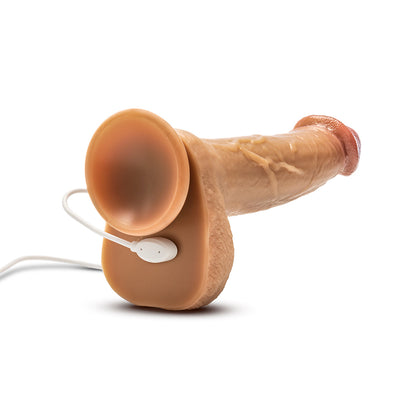 Tan realistic silicone dildo with suction cup base and attached white remote control on white background.