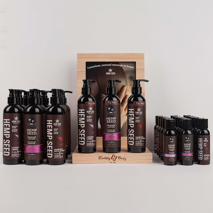 Earthly Body Hemp Seed Massage Lotion set with large and travel bottles in Lavender, Skinny Dip, and Kashmir Musk scents displayed on wooden stand