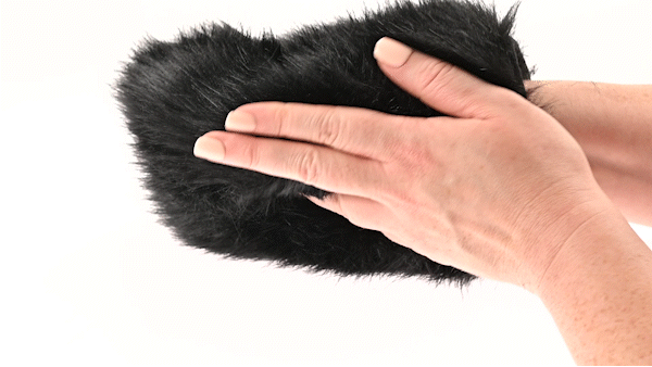 Hands wearing a black faux fur sensory mitt with hidden spikes for contrasting soft and prickly sensations.