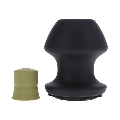 Large black silicone Kum Keeper plug with removable green stopper shown side by side on white background.