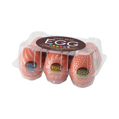 Clear plastic egg carton containing six Tenga EGG Variety Pack Hard Boiled II textured sleeves in orange packaging.