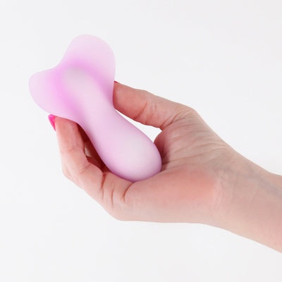 Hand holding a small, pebble-shaped purple silicone vibrator with translucent wings and a smooth matte finish.