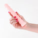 Hand holding a translucent peach-colored textured silicone vibrator with a beaded design against a white background.