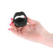 Hand holding a black silicone vibrating cock ring with a modern ergonomic design against a white background.