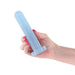 Hand holding a small, smooth, light blue silicone dildo with a flat suction base against a white background.