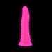 Glow-in-the-dark pink textured silicone dildo with a suction base on black background