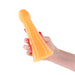 Hand holding a large, glossy orange glow-in-the-dark silicone dildo with a tapered, textured design.