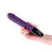 Hand holding a purple phallic vibrator with textured silicone shaft and black base featuring control buttons.