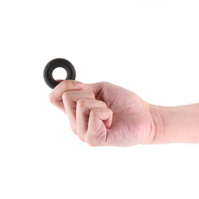 Hand holding a small black silicone ring against a white background.