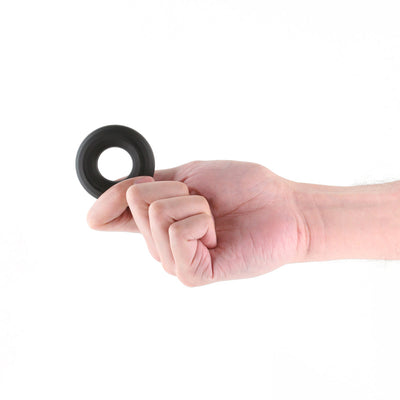 Hand holding a medium-sized black silicone Renegade Fireman Ring against a white background.