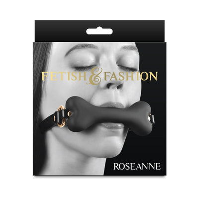 Packaging of Fetish & Fashion Roseanne black bone-shaped breathable gag with adjustable strap shown on model with closed eyes.