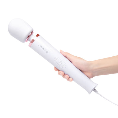 Hand holding Le Wand Plugin Sky White vibrating massager with long cord and control buttons visible