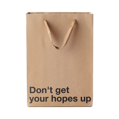 Brown kraft gift bag with brown ribbon handles and bold black text reading Don't get your hopes up.
