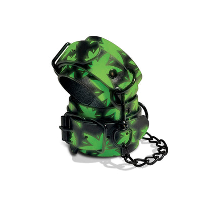 Green and black glow-in-the-dark wrist cuffs with cannabis leaf pattern and black metal chain and buckles.