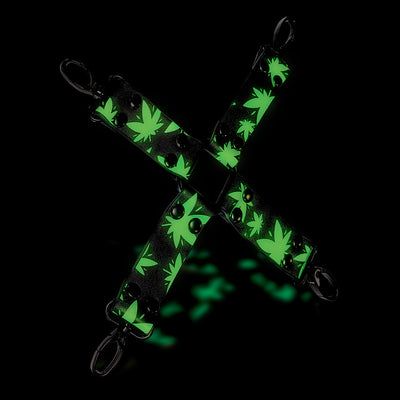 Glow-in-the-dark black hogtie with green cannabis leaf pattern and metal clips in an X shape on black background.