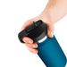 Hand holding a blue discreet water bottle stroker with black flip-top lid and thumb ring grip.