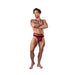 Muscular man wearing burgundy lace cutout strappy thong standing with arms crossed on white background.