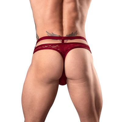 Back view of a male model wearing a burgundy strappy cutout thong with lace detailing and elastic waistband straps.