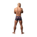 Rear view of a man wearing Male Power Hazy Dayz pouch shorts with colorful mushroom print on black fabric.