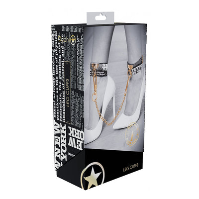 Packaging of Ouch! NY Collection Leg Cuffs showing black and white leg cuffs with gold chain worn with white high heels.