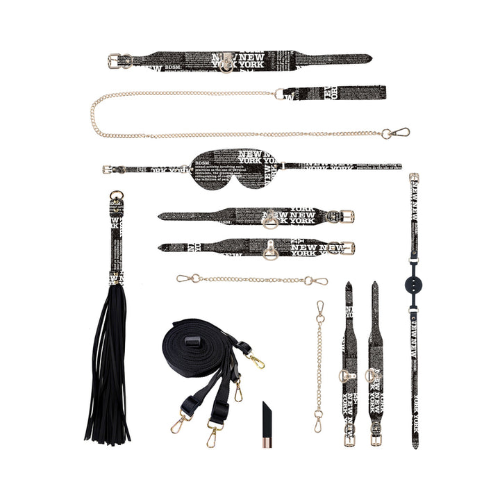 Ouch! NY Collection Kit with black and white text print restraints, blindfold, flogger, leash, and accessories arranged on white background.