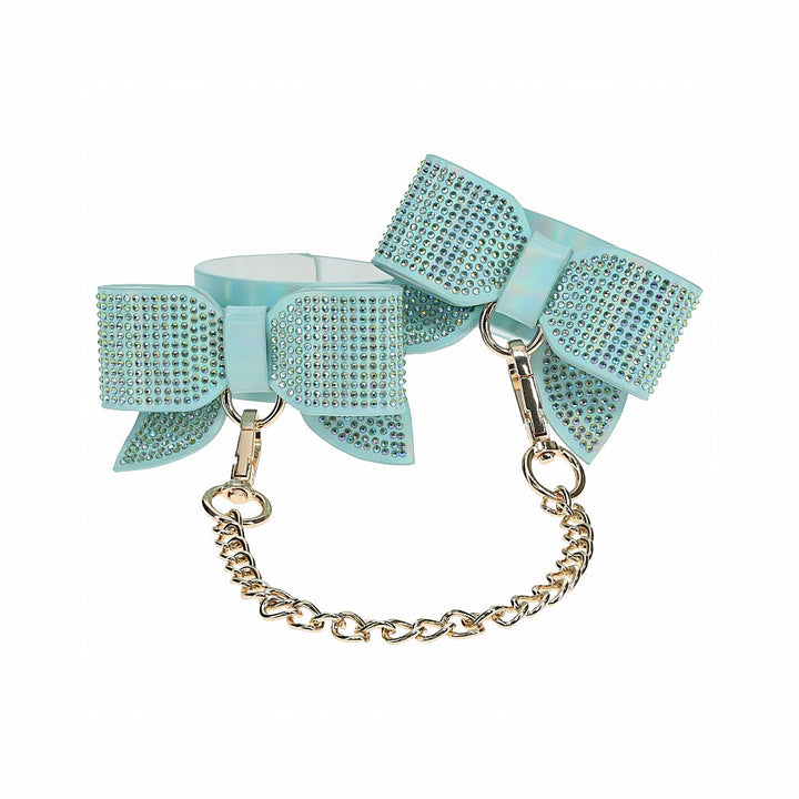 Light blue bow-shaped handcuffs adorned with rhinestones and connected by a gold chain.
