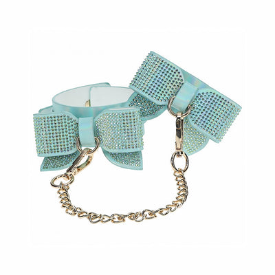 Light blue iridescent leg cuffs with rhinestone-studded bows and gold chain connectors.