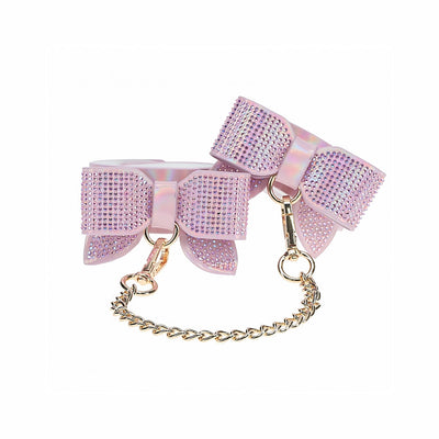 Iridescent pink leg cuffs with rhinestone-studded bows and gold chain connectors for adjustable fit and style.
