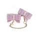 Iridescent pink leg cuffs with rhinestone-studded bows and gold chain connectors for adjustable fit and style.