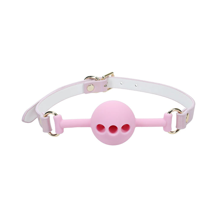 Pink silicone ball gag with three ventilation holes and adjustable white and pink bonded leather straps with gold hardware.