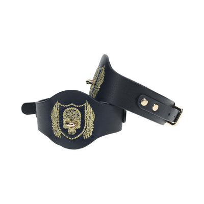 Black bonded leather leg cuffs with gold embroidered crest and iridescent hardware, adjustable with buckle closure.