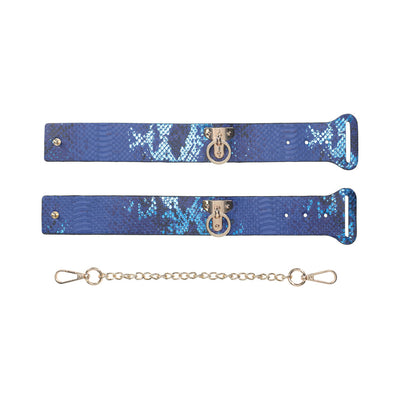 Blue snakeskin-patterned bonded leather handcuffs with iridescent hardware and detachable gold chain.
