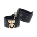 Black textured bonded leather handcuffs with gold-tone iridescent hardware and adjustable straps.