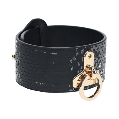 Black faux snakeskin leather handcuff with gold-tone hardware and a circular ring detail.