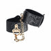 Black bonded leather leg cuffs with snake skin texture and iridescent gold chain and hardware detailing.