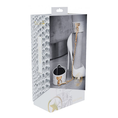 Packaging of Ouch! Florence Collection Leg Cuffs featuring white bonded leather cuffs with gold chain and hardware, styled on a model's leg.