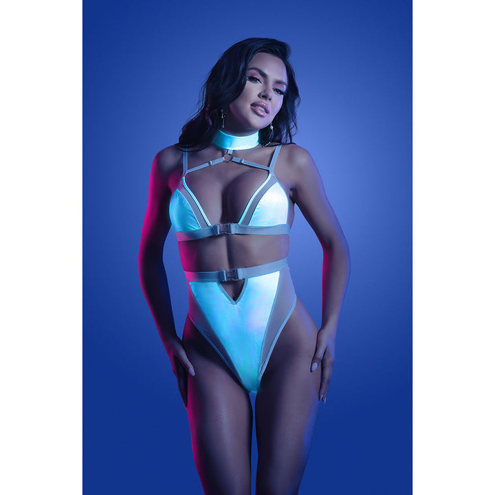 Model wearing a light blue iridescent glow-in-the-dark cut-out harness bodysuit with adjustable straps against a blue background.