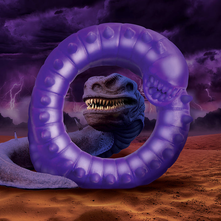 Purple translucent silicone ring with textured spikes and a toothy worm design, set against a stormy desert background.