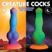 Glow-in-the-dark silicone alien dildo with vibrant blue, purple, and orange hues by day and glowing green by night.