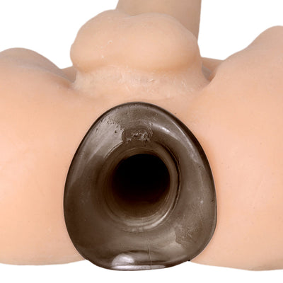 Close-up of a black hollow tunnel anal plug inserted in a flesh-toned silicone model.
