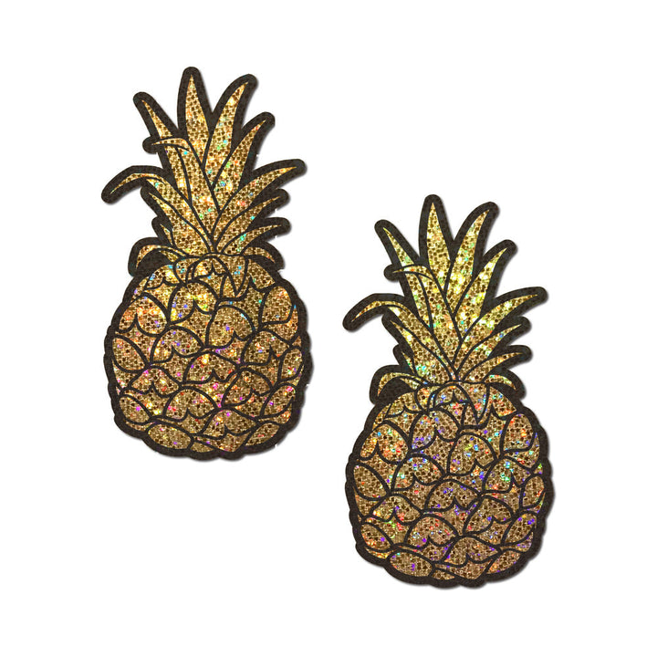 Pair of gold glitter pineapple-shaped nipple covers with black etched details on a white background