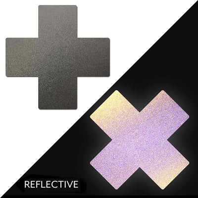 Pair of gun metal grey cross-shaped reflective nipple pasties shown in normal and illuminated light conditions.