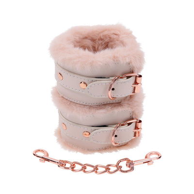 Light peach faux fur handcuffs with rose gold hardware and adjustable buckles, connected by a matching chain.