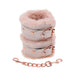 Light peach faux fur handcuffs with rose gold hardware and adjustable buckles, connected by a matching chain.
