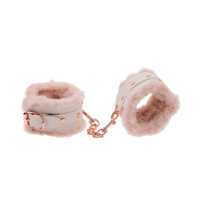 Peach-colored faux fur handcuffs with rose gold hardware and adjustable buckle, connected by a short chain.