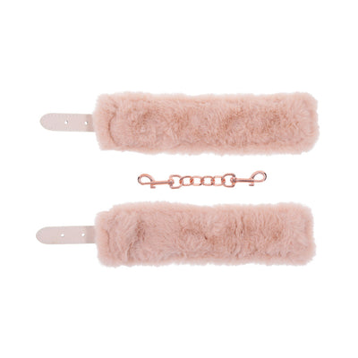 Peach-colored faux fur handcuffs with adjustable straps and rose gold chain connector on white background.